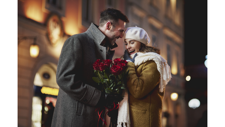 Man giving his amazed girlfriend bunch of red roses on Valentine's Day