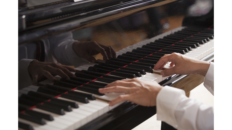 Close up of a pianists hands, playing on a grand piano.