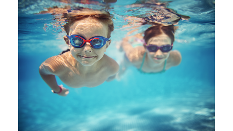 Happy kids swimming underwater in pool