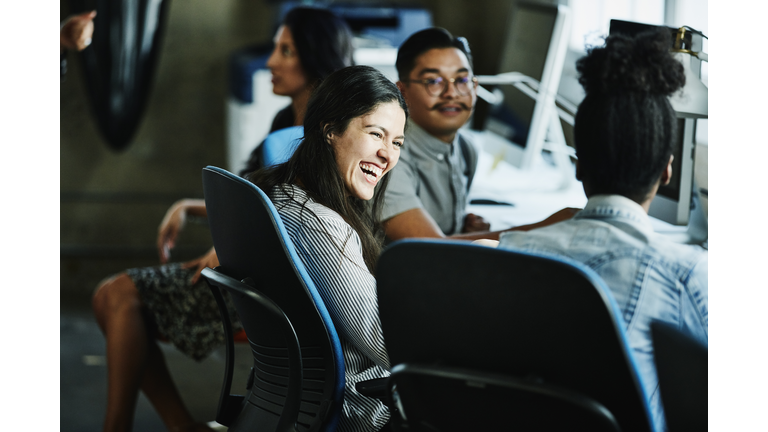 Businesswoman laughing with coworkers while working in design studio