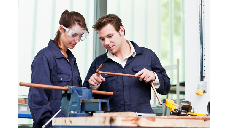 Professional plumber with apprentice in class