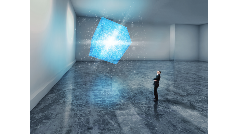 man looking up at a glowing blue 3D cube