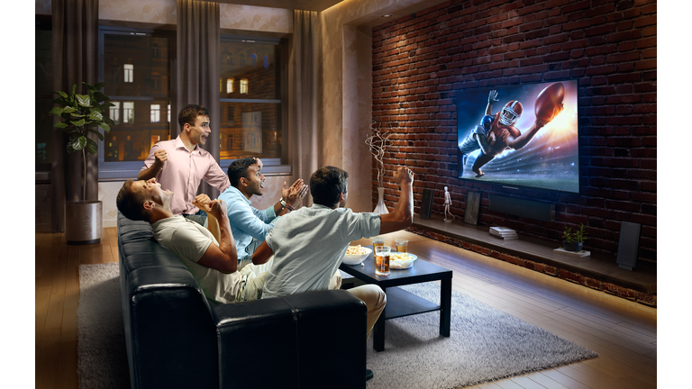 Young men cheering and watching American football game on TV