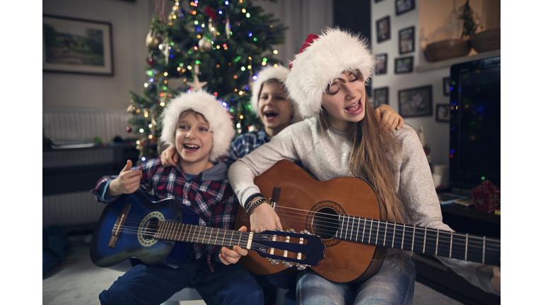 Children singing Christmas carols near Christmas tree