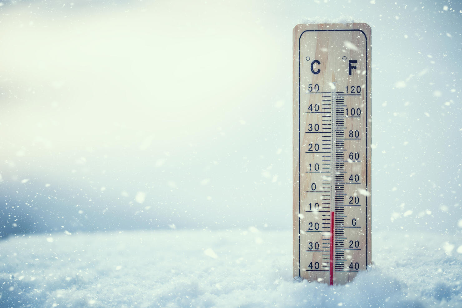 Thermometer on snow shows low temperatures under zero. Low temperatures in degrees Celsius and fahrenheit. Cold winter weather ten under zero