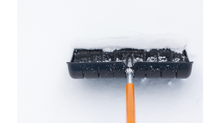 Snow shovel in snow, during snowfall. Shoveling the snow