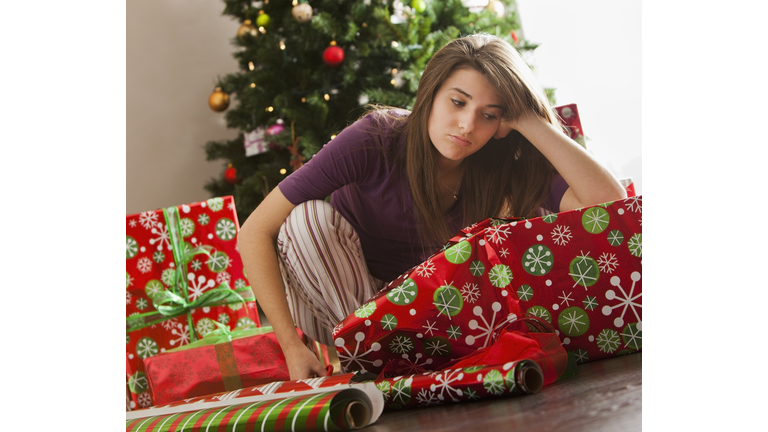 Bored Caucasian woman wrapping Christmas gifts