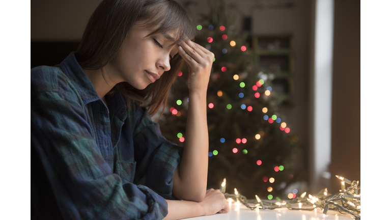 Mixed Race woman with headache near Christmas tree