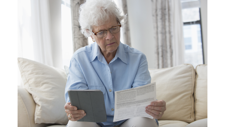 Older Caucasian woman using digital tablet to pay bills