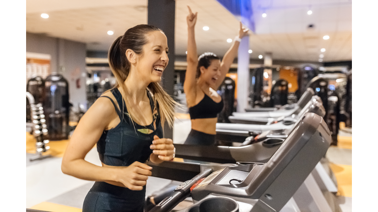 Two happy women working out in gym on a treadmil