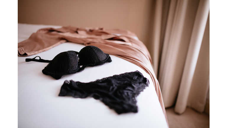 Lace lingerie and silk robe placed on bed