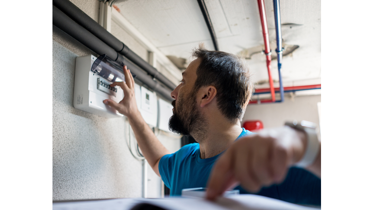 Man in boiler and heating room using control device display for smart home