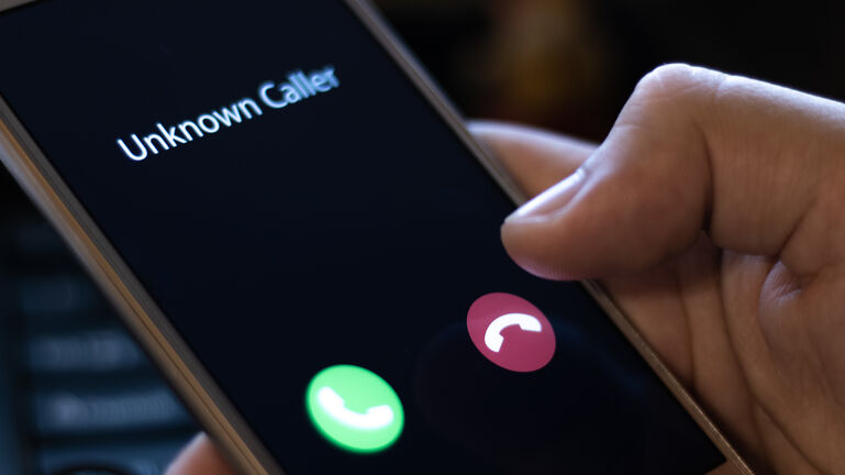 Unknown caller. A man holds a phone in his hand and thinks to end the call. Incoming from an unknown number at night. Incognito or anonymous