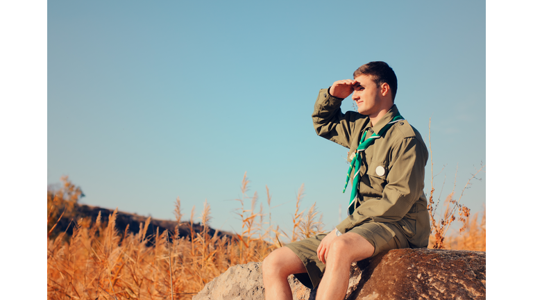 Boy Scout Sitting on Rock Watching Over the Field