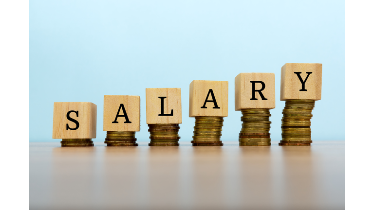 Salary text written on wooden block with stacked coins