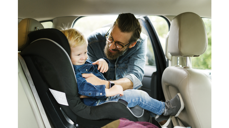 Man putting his son into car seat