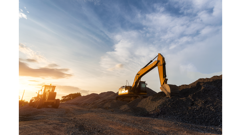 Backhoe used in construction, Big excavator on new construction site, in the background the blue sky and sun.