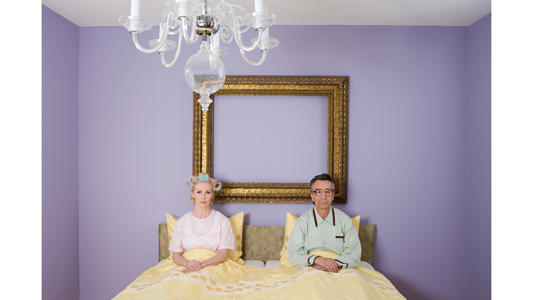 Couple in bed looking miserable