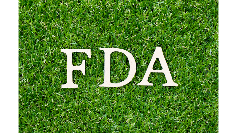 Wood letter block in word FDA (abbreviation of food and drug administration) on artificial green grass background