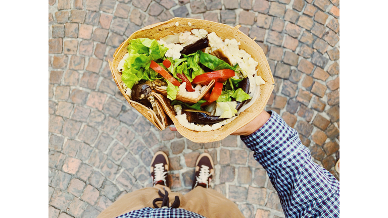 Eating big French crepe pancake with vegetables, salad and cheese, personal persoective view