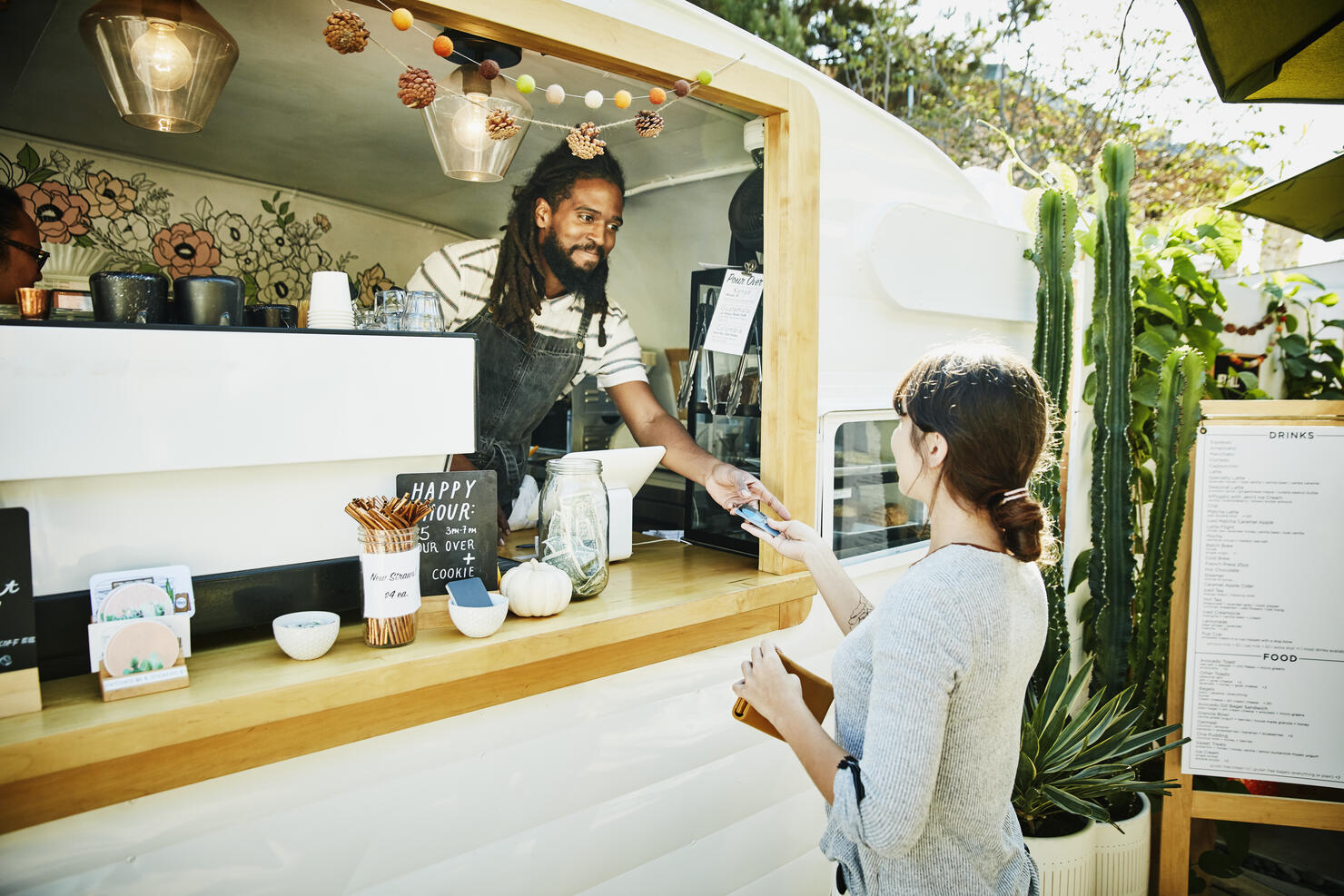 Smiling food truck owner taking credit card for payment from customer