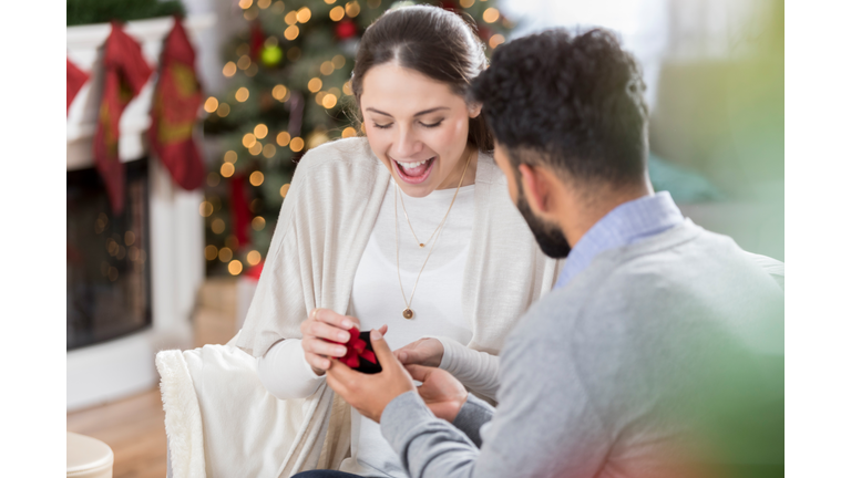 Young woman is surprised as her boyfriend proposes to her