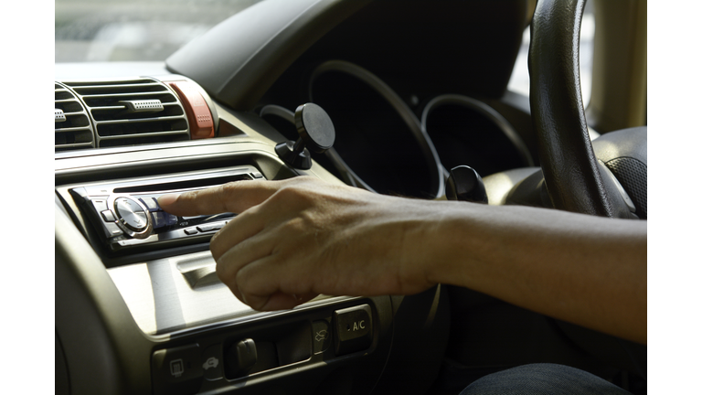 Man hand on turn on radio in the car