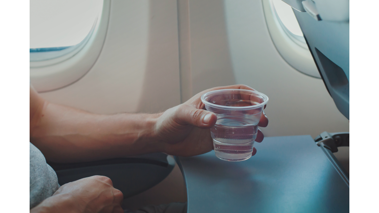 Passenger drinking water in airplane during flight.