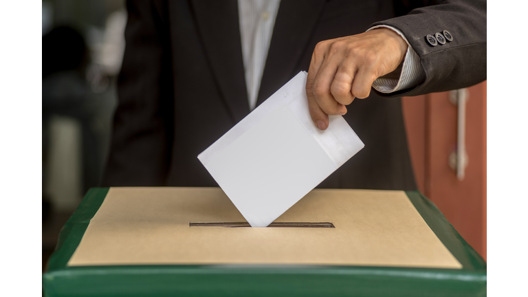 Hand of a person casting a vote into the ballot box during elections