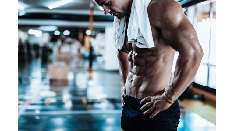 Young man tired after training showing his abdominal muscles