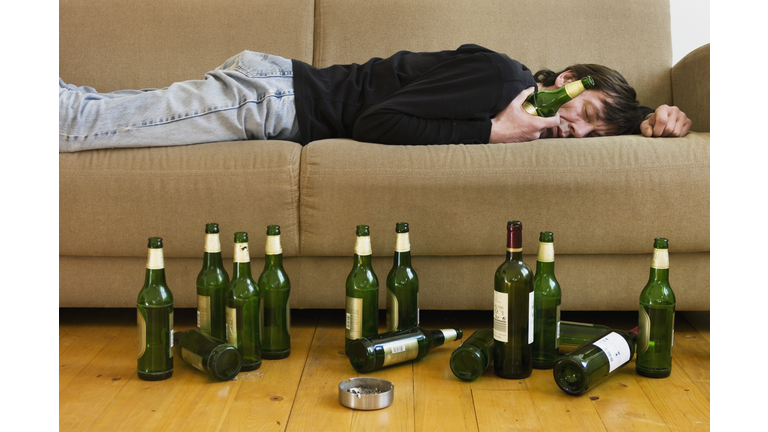 Germany, Hessen, Frankfurt, Drunk man lying on sofa with empty beer bottles