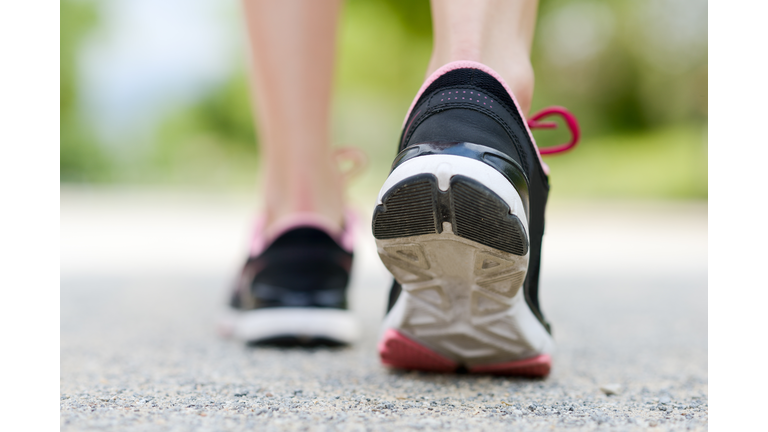 Low Section Of Woman Wearing Shoes Walking On Road