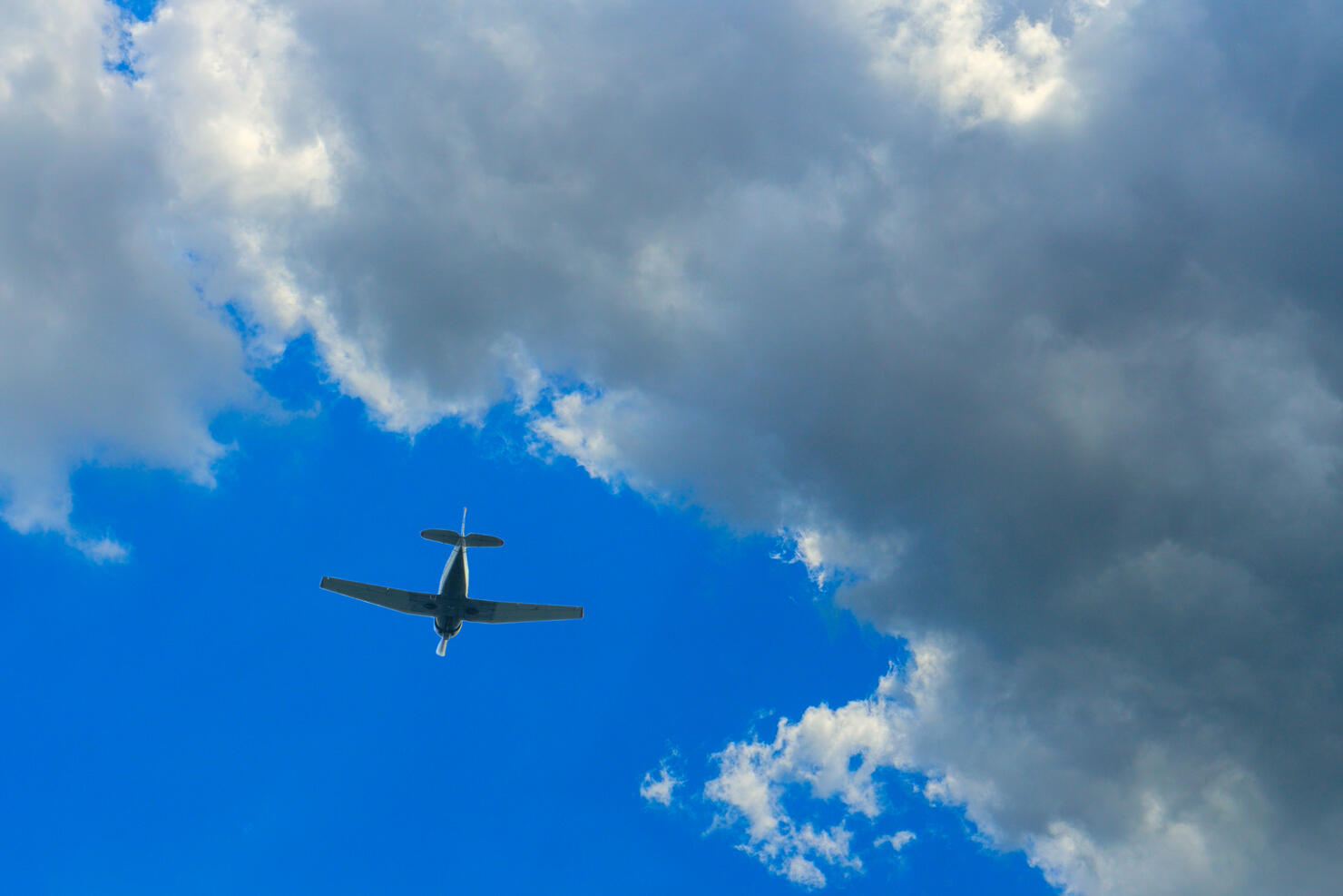 Single-engine aircraft in the bright sky against the backdrop of a thundercloud. Concept of air show, aerobatic flying, plane crash