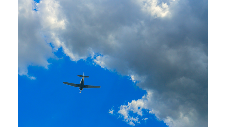 Single-engine aircraft in the bright sky against the backdrop of a thundercloud. Concept of air show, aerobatic flying, plane crash