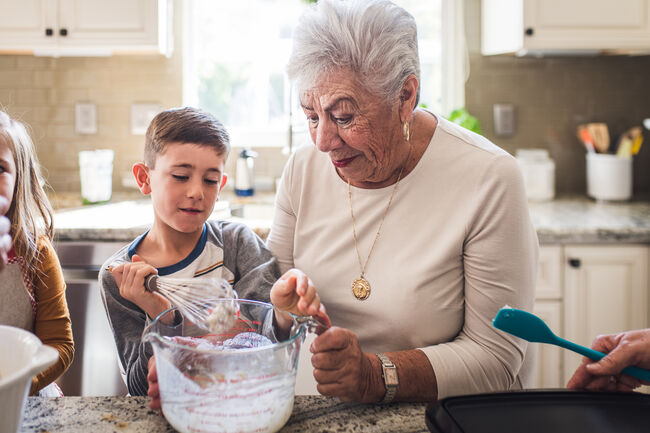 Grandson and great grandma making breakfast pancakes in the kitchen