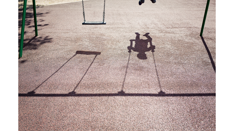 Shadow of a child on a playground swing