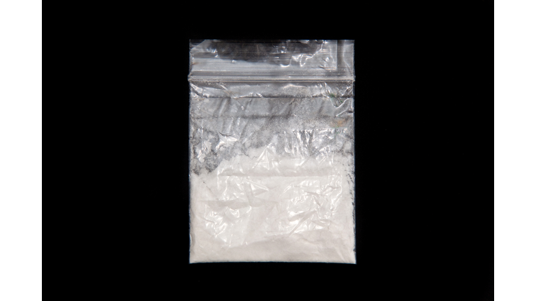 Plastic bag of white powdered mephedrone on black background