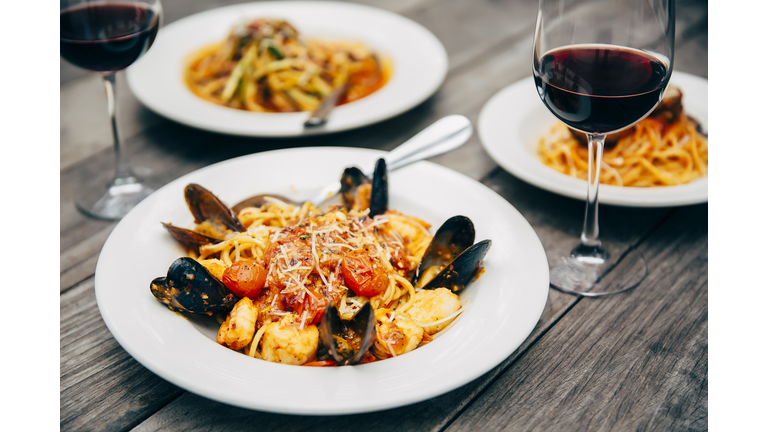 Plates of seafood and pasta with wine glasses