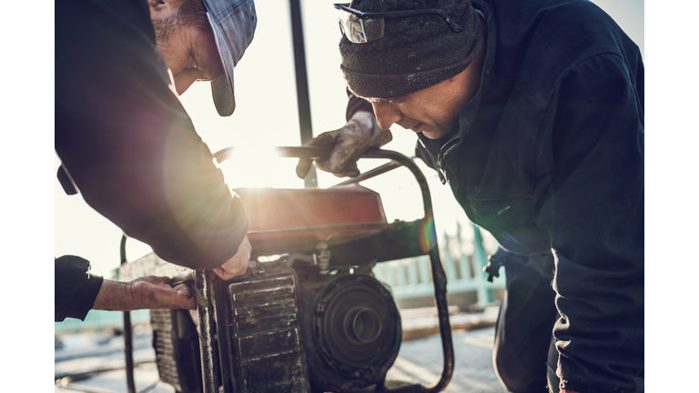 Manual workers repairing power generator.