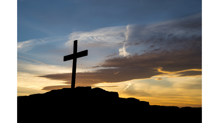 Wooden cross on a hilltop at sunset