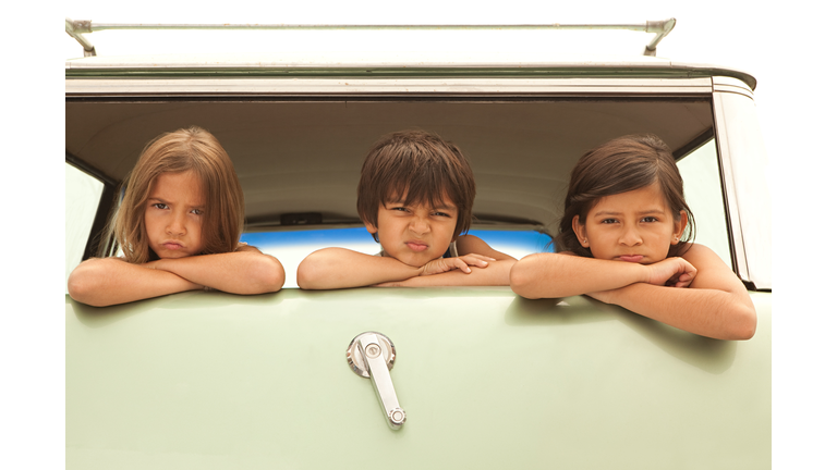 Three sullen children in back of estate car