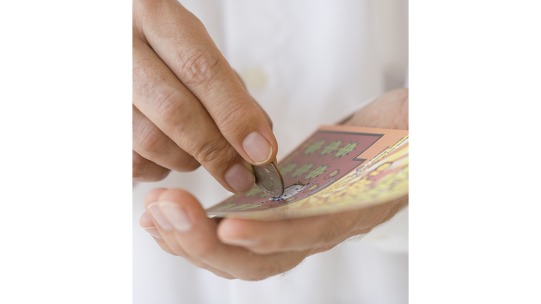 Man scratching lottery card with coin