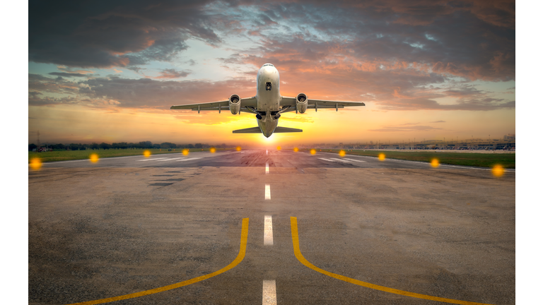 Airplane taking off from the airport runway in beautiful sunset light