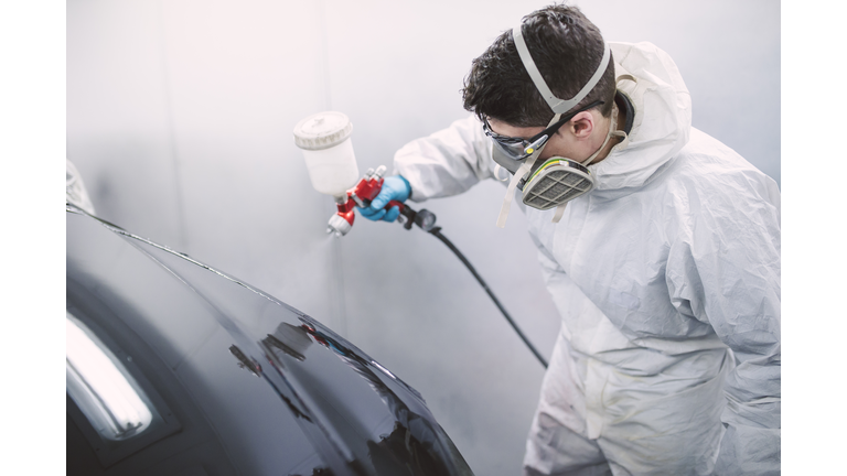 Auto painter painting a car inside a paint booth