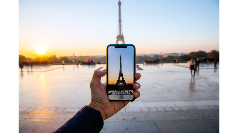 Tourist taking picture of Eiffel Tower with smart phone, personal perspective view, Paris, France