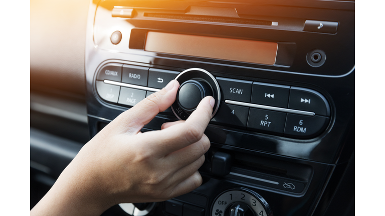 Woman turning button of radio in car