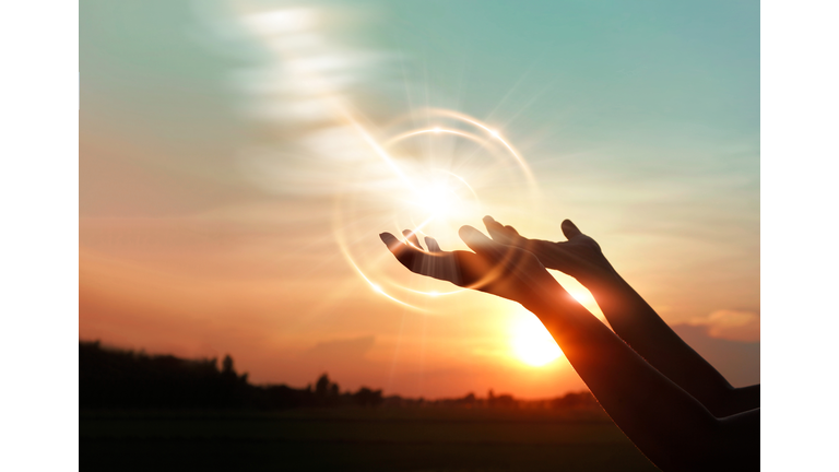 Woman hands praying for blessing from god on sunset background