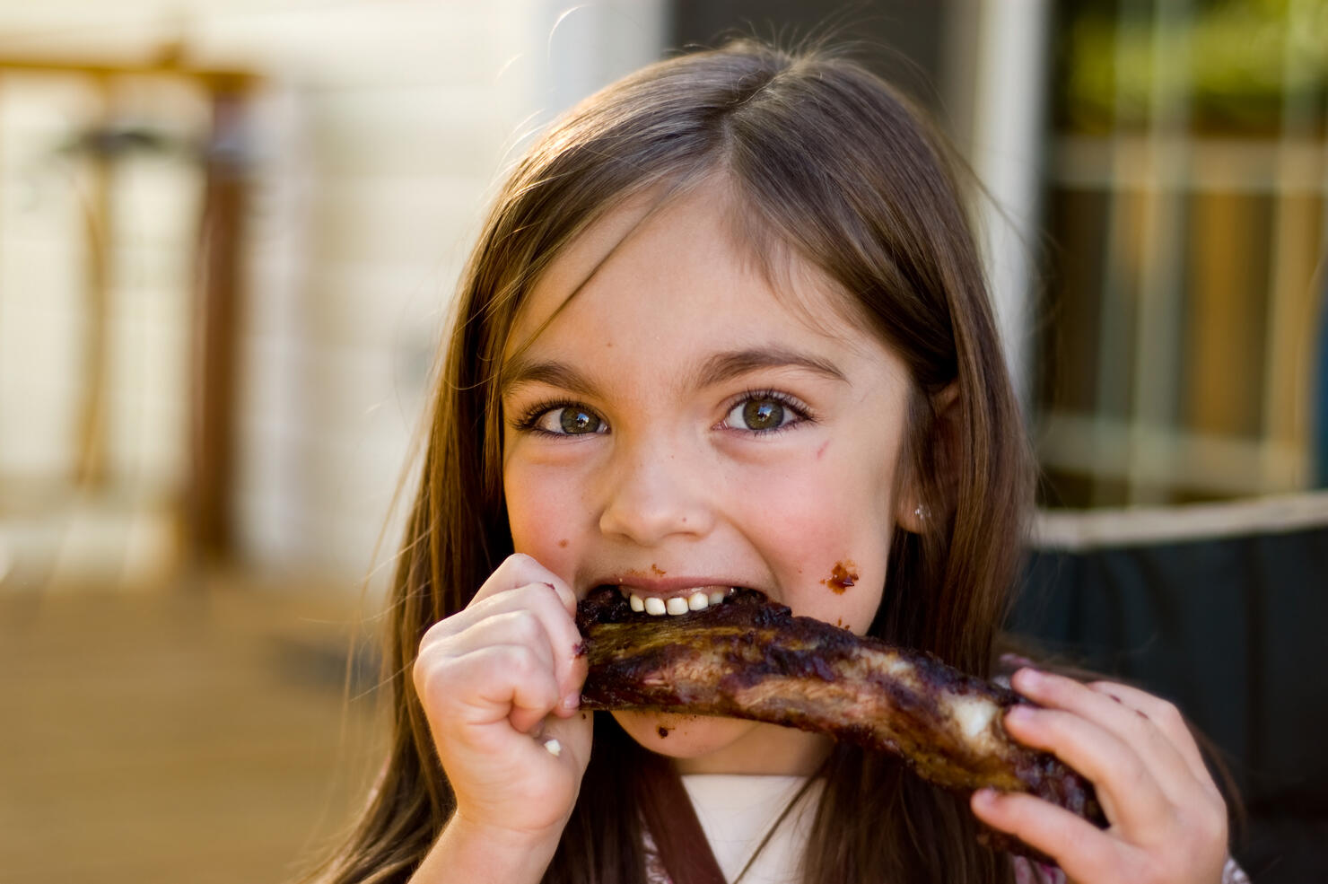 A young girl chowing down on a rib