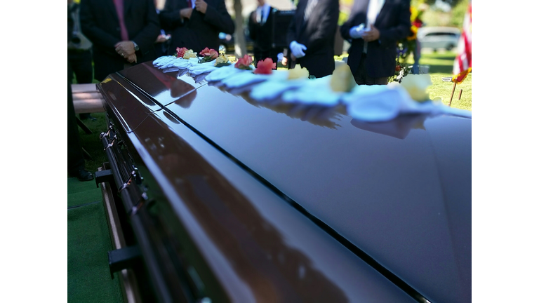 Close-Up Of Decorated Coffin Against Men At Funeral