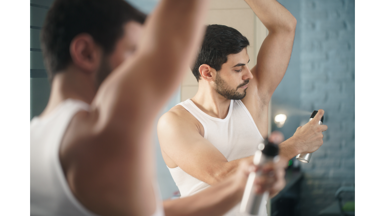 Man Using Spray Deodorant On Underarm For Bad Smell